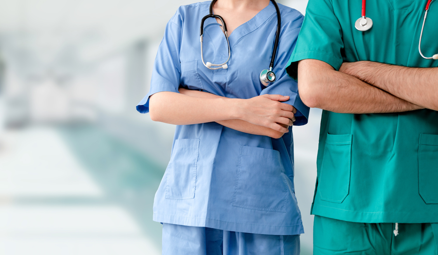 Two hospital staffs - surgeon, doctor or nurse standing with arms crossed in the hospital. Medical healthcare and doctor service.